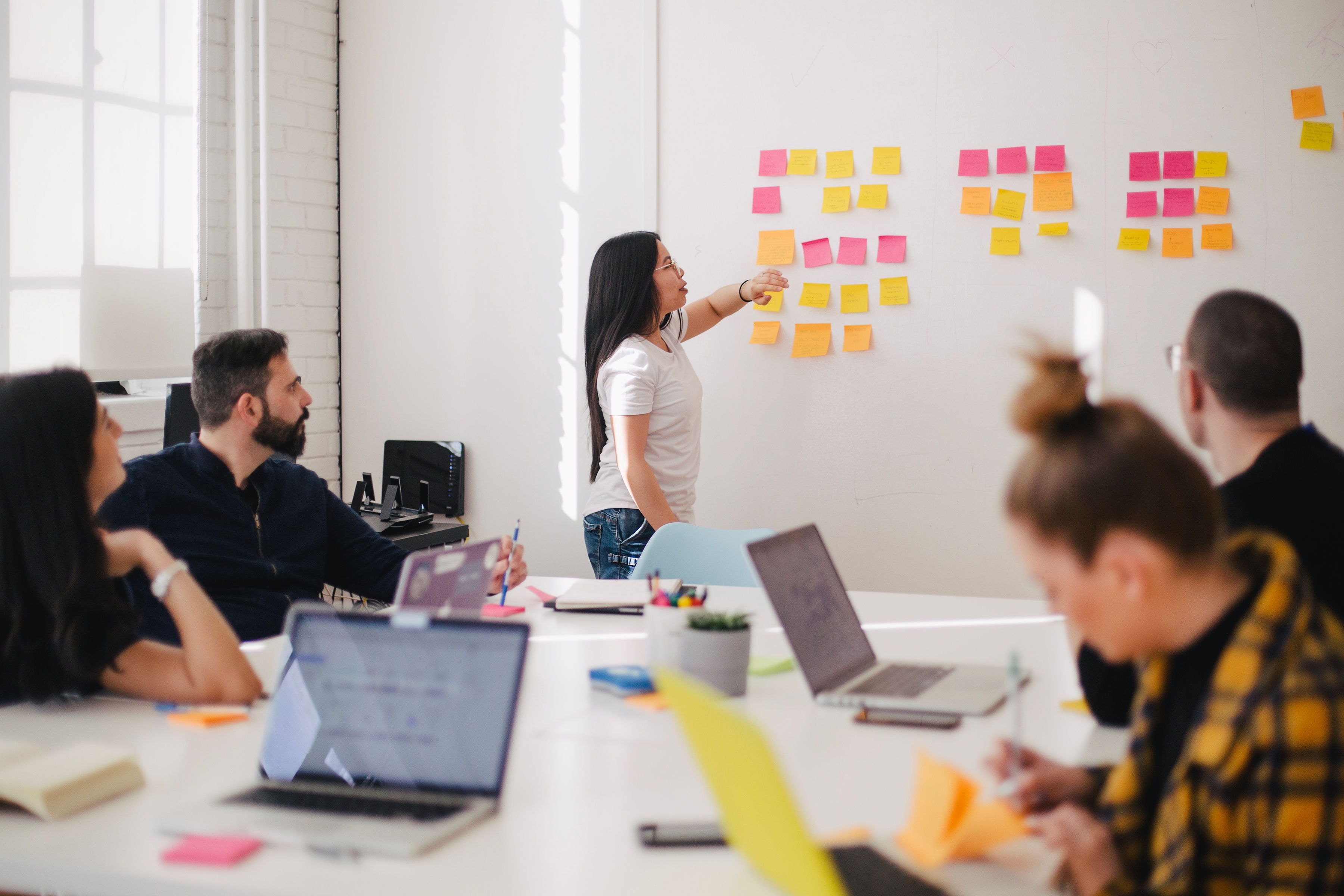 Team in a meeting collaborating with sticky notes on a wall