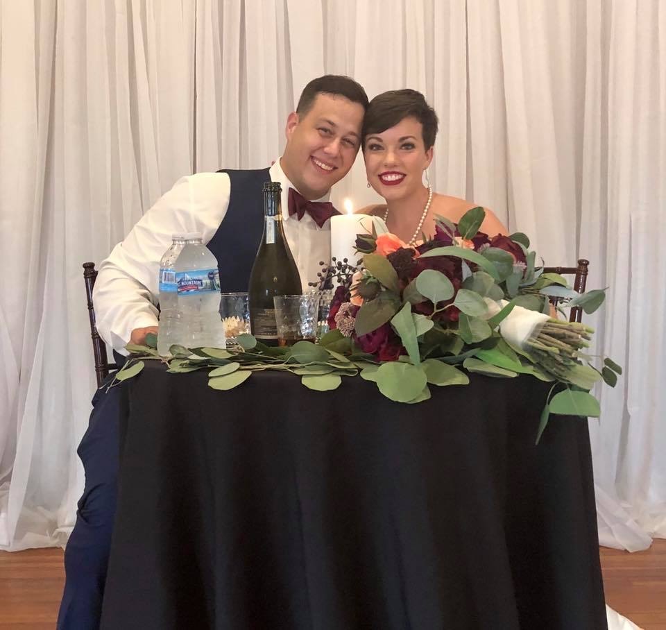 Bride and groom smiling together at a sweetheart table