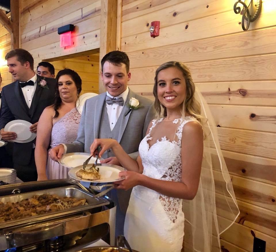 Bride and groom serving themselves from a buffet line at a wedding reception