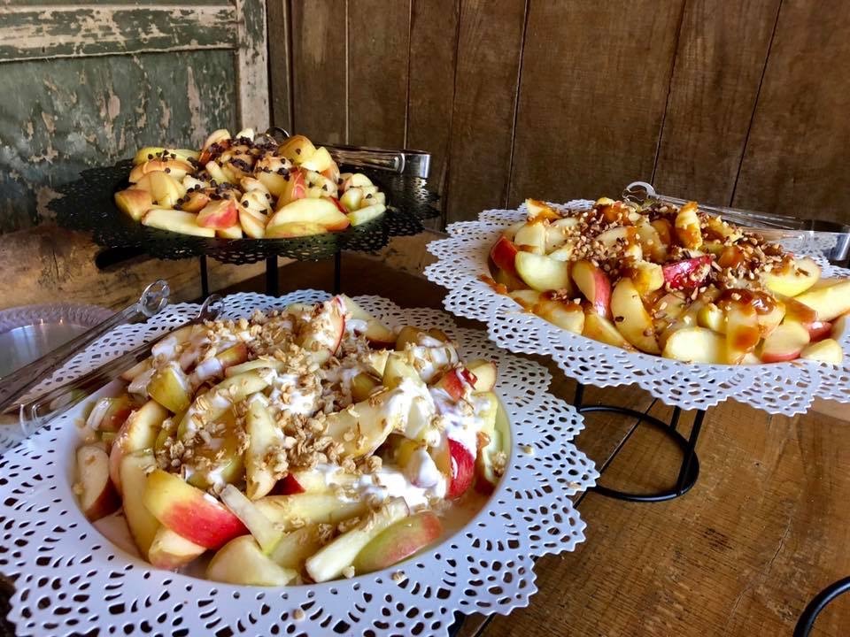 Sliced apples with caramel, yogurt, and toppings on platters
