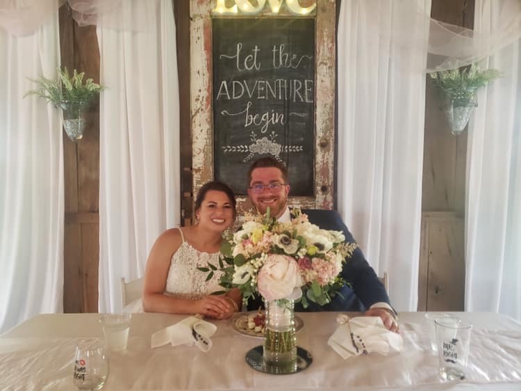 Bride and groom smiling behind a sweetheart table